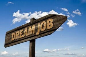 A wooden signpost with the words 'DREAM JOB' in bold letters, pointing toward a bright blue sky with scattered white clouds, symbolizing the pursuit of top in-demand jobs in 2025 such as AI careers, data science roles, cybersecurity jobs, healthcare careers, and renewable energy positions. The image inspires career opportunities in high-paying fields like software development, big data analytics, telemedicine, and sustainable energy, highlighting skills for the future such as machine learning, project management, and ethical hacking.